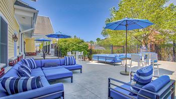 Outdoor patio and grills with blue couches and umbrellas at Windsor Ridge at Westborough, Westborough, MA